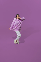 Image showing High angle view of young woman on purple studio background. Girl in motion or movement. Human emotions and facial expressions concept