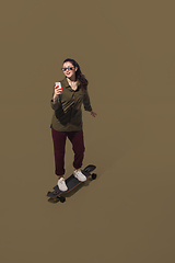 Image showing High angle view of young woman on brown studio background. Girl in motion or movement. Human emotions and facial expressions concept