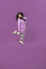 Image showing High angle view of young woman on purple studio background. Girl in motion or movement. Human emotions and facial expressions concept