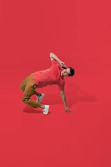 Image showing High angle view of young man on red studio background. Boy in motion, jumping high. Human emotions and facial expressions concept