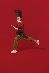 Image showing High angle view of young woman on red studio background. Girl in motion or movement. Human emotions and facial expressions concept