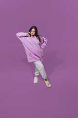 Image showing High angle view of young woman on purple studio background. Girl in motion or movement. Human emotions and facial expressions concept