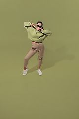 Image showing High angle view of young woman on green studio background. Girl in motion or movement. Human emotions and facial expressions concept