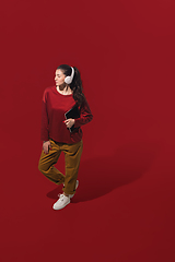 Image showing High angle view of young woman on red studio background. Girl in motion or movement. Human emotions and facial expressions concept