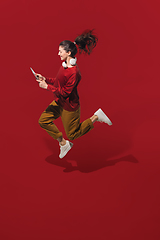 Image showing High angle view of young woman on red studio background. Girl in motion or movement. Human emotions and facial expressions concept