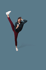 Image showing High angle view of young woman on blue studio background. Girl in motion or movement. Human emotions and facial expressions concept