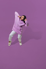 Image showing High angle view of young woman on purple studio background. Girl in motion or movement. Human emotions and facial expressions concept