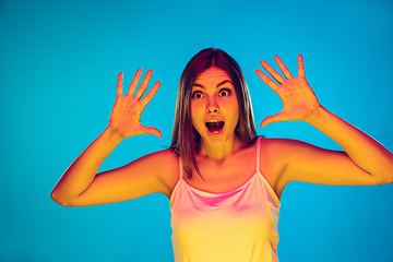 Image showing Caucasian young woman\'s portrait isolated on blue background in neon light