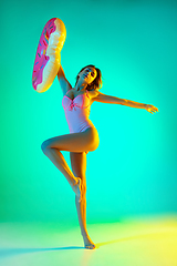 Image showing Beautiful girl in fashionable swimsuit isolated on gradient studio background in neon light. Summer, resort, fashion and weekend concept