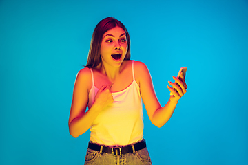 Image showing Caucasian young woman\'s portrait isolated on blue background in neon light