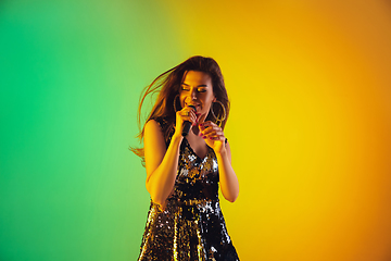 Image showing Caucasian female singer portrait isolated on gradient studio background in neon light
