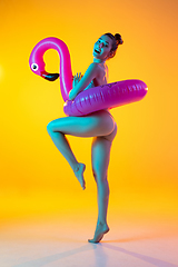 Image showing Fashion portrait of seductive girl in stylish swimwear posing on a bright yellow background. Summertime, beach season