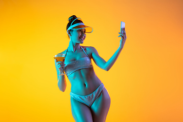 Image showing Fashion portrait of seductive girl in stylish swimwear posing on a bright yellow background. Summertime, beach season