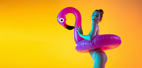 Image showing Fashion portrait of seductive girl in stylish swimwear posing on a bright yellow background. Summertime, beach season