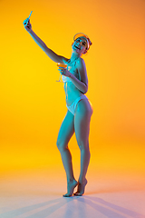 Image showing Fashion portrait of seductive girl in stylish swimwear posing on a bright yellow background. Summertime, beach season