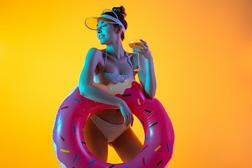 Image showing Fashion portrait of seductive girl in stylish swimwear posing on a bright yellow background. Summertime, beach season