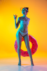 Image showing Fashion portrait of seductive girl in stylish swimwear posing on a bright yellow background. Summertime, beach season