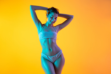 Image showing Fashion portrait of seductive girl in stylish swimwear posing on a bright yellow background. Summertime, beach season