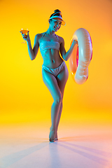 Image showing Fashion portrait of seductive girl in stylish swimwear posing on a bright yellow background. Summertime, beach season