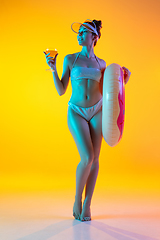 Image showing Fashion portrait of seductive girl in stylish swimwear posing on a bright yellow background. Summertime, beach season