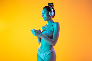 Image showing Fashion portrait of seductive girl in stylish swimwear posing on a bright yellow background. Summertime, beach season