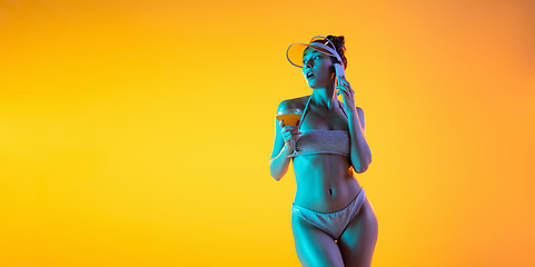 Image showing Fashion portrait of seductive girl in stylish swimwear posing on a bright yellow background. Summertime, beach season