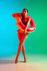 Image showing Fashion portrait of seductive girl in stylish swimwear posing on a bright gradient background. Summertime, beach season