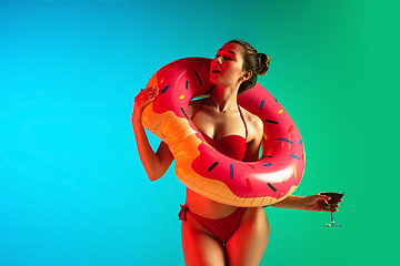 Image showing Fashion portrait of seductive girl in stylish swimwear posing on a bright gradient background. Summertime, beach season