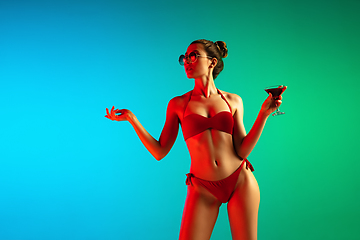 Image showing Fashion portrait of seductive girl in stylish swimwear posing on a bright gradient background. Summertime, beach season