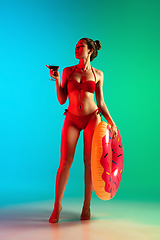 Image showing Fashion portrait of seductive girl in stylish swimwear posing on a bright gradient background. Summertime, beach season