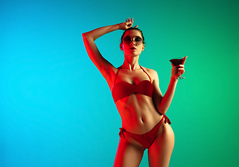Image showing Fashion portrait of seductive girl in stylish swimwear posing on a bright gradient background. Summertime, beach season