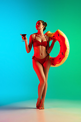 Image showing Fashion portrait of seductive girl in stylish swimwear posing on a bright gradient background. Summertime, beach season