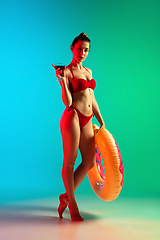 Image showing Fashion portrait of seductive girl in stylish swimwear posing on a bright gradient background. Summertime, beach season