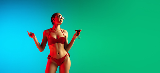 Image showing Fashion portrait of seductive girl in stylish swimwear posing on a bright gradient background. Summertime, beach season