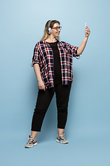 Image showing Young caucasian woman in casual wear on blue background. Bodypositive female character, plus size businesswoman