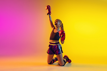 Image showing Little caucasian female kick boxer training on gradient background in neon light, active and expressive