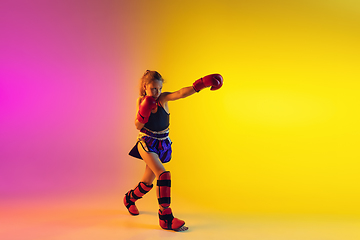 Image showing Little caucasian female kick boxer training on gradient background in neon light, active and expressive