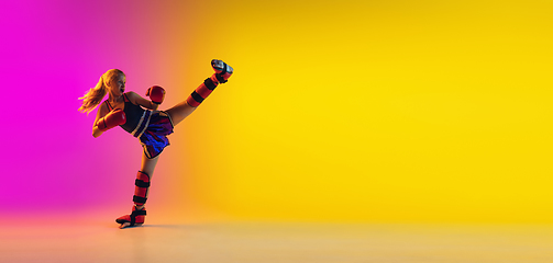 Image showing Little caucasian female kick boxer training on gradient background in neon light, active and expressive