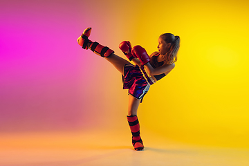 Image showing Little caucasian female kick boxer training on gradient background in neon light, active and expressive