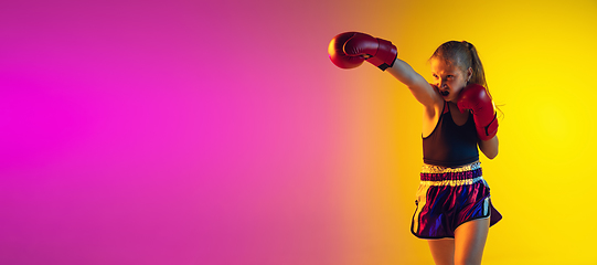 Image showing Little caucasian female kick boxer training on gradient background in neon light, active and expressive