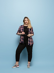 Image showing Young caucasian woman in casual wear on blue background. Bodypositive female character, plus size businesswoman