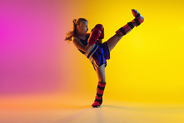 Image showing Little caucasian female kick boxer training on gradient background in neon light, active and expressive