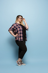 Image showing Young caucasian woman in casual wear on blue background. Bodypositive female character, plus size businesswoman
