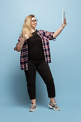 Image showing Young caucasian woman in casual wear on blue background. Bodypositive female character, plus size businesswoman