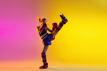 Image showing Little caucasian female kick boxer training on gradient background in neon light, active and expressive