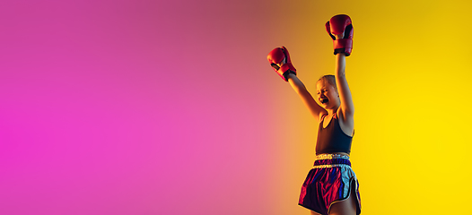 Image showing Little caucasian female kick boxer training on gradient background in neon light, active and expressive