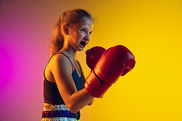 Image showing Little caucasian female kick boxer training on gradient background in neon light, active and expressive