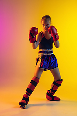 Image showing Little caucasian female kick boxer training on gradient background in neon light, active and expressive