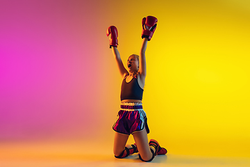 Image showing Little caucasian female kick boxer training on gradient background in neon light, active and expressive