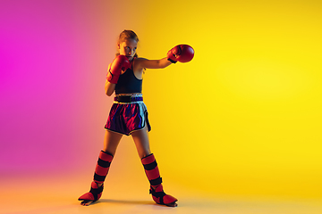 Image showing Little caucasian female kick boxer training on gradient background in neon light, active and expressive